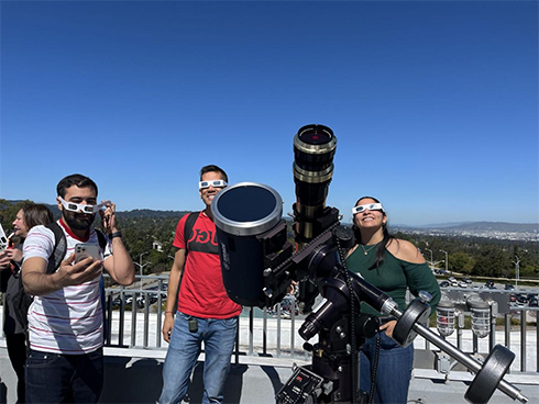 Felipe Aguado, Alejandro Caro and Catalina use telescopes and glasses to catch a glimpse of a rare solar eclipse at the College of San Mateo observatory. Photo by Holly Rusch/Daily Journal.